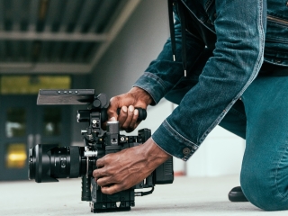 A Man Kneeling Down Next To A Camera