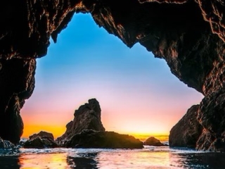 A View Of The Sunset Through A Cave