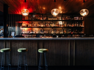A Bar With Stools And A Shelf Of Liquor